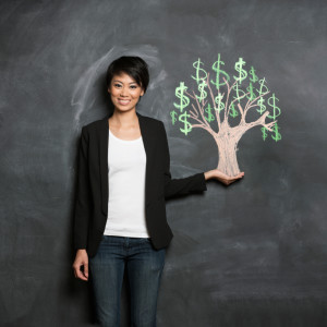 Happy Asian Business woman in front of chalk money tree drawing on blackboard.